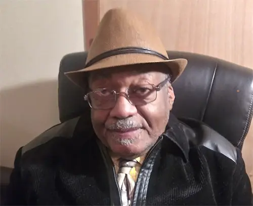 Portrait of Derwyn Golden wearing a tan hat and glasses